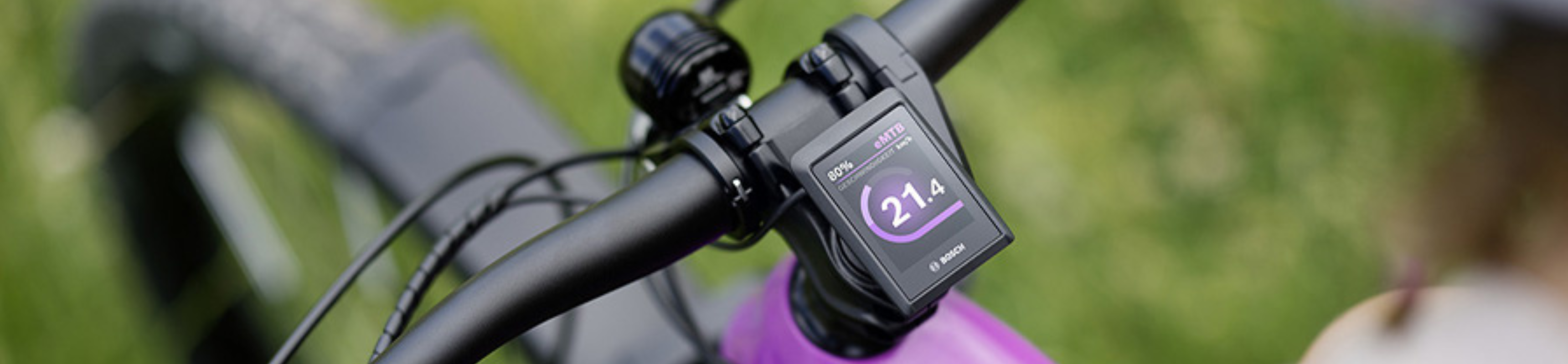 Bosch Smart System Display am Fahrradlenker – zeigt Geschwindigkeit und Akkustand, montiert auf einem violetten E-Bike.